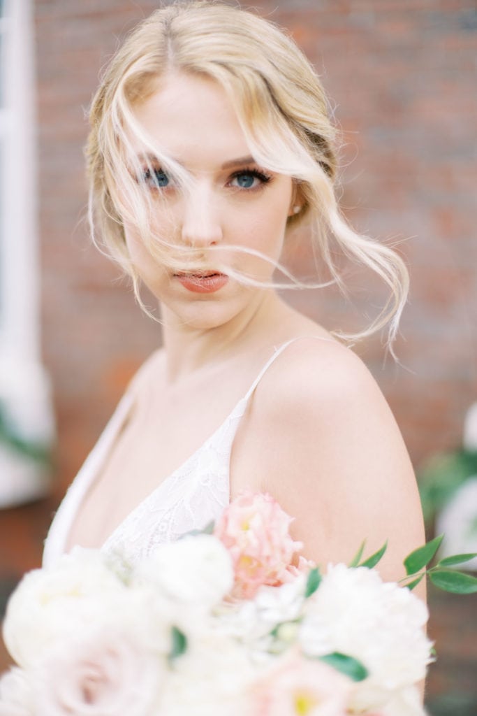 Close up shot of a bride with wisps of hair flowing across her face as she stares at the camera. Must-have wedding photos by Marcela Plosker, a Boston wedding photographer.
