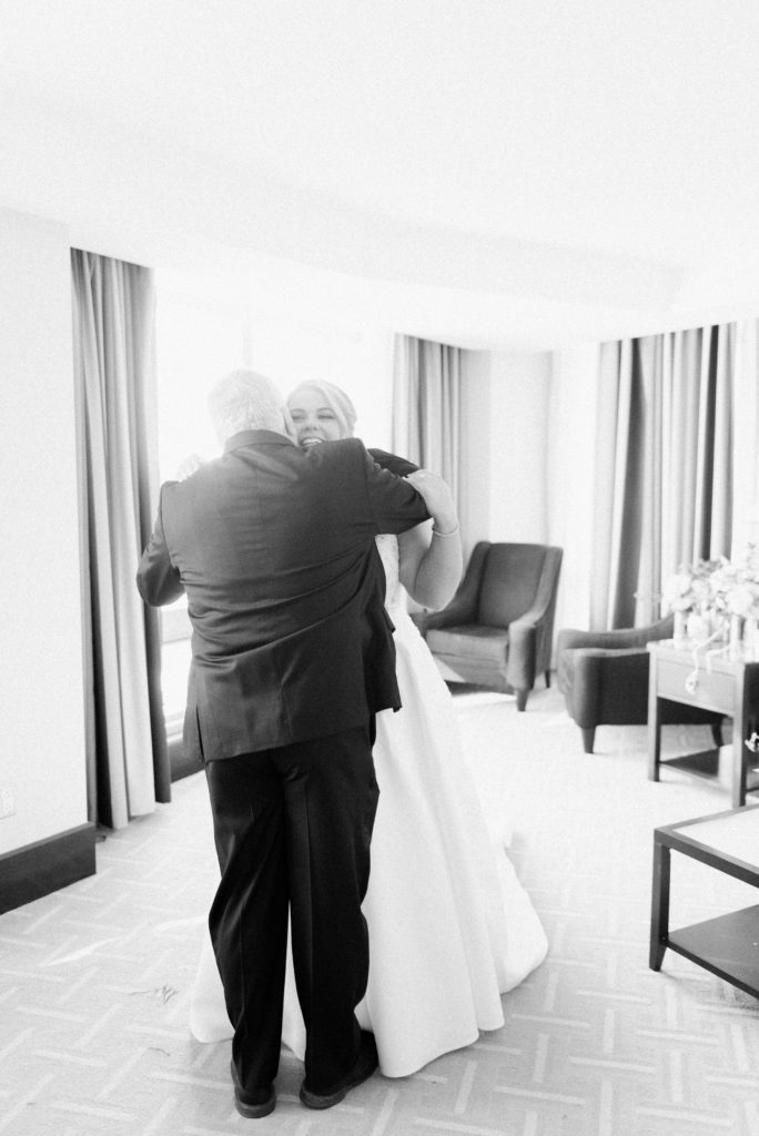 A father embraces his daughter on her wedding day after the "first look" of seeing her in her wedding dress. Must-have wedding photos by Marcela Plosker, a Boston wedding photographer.