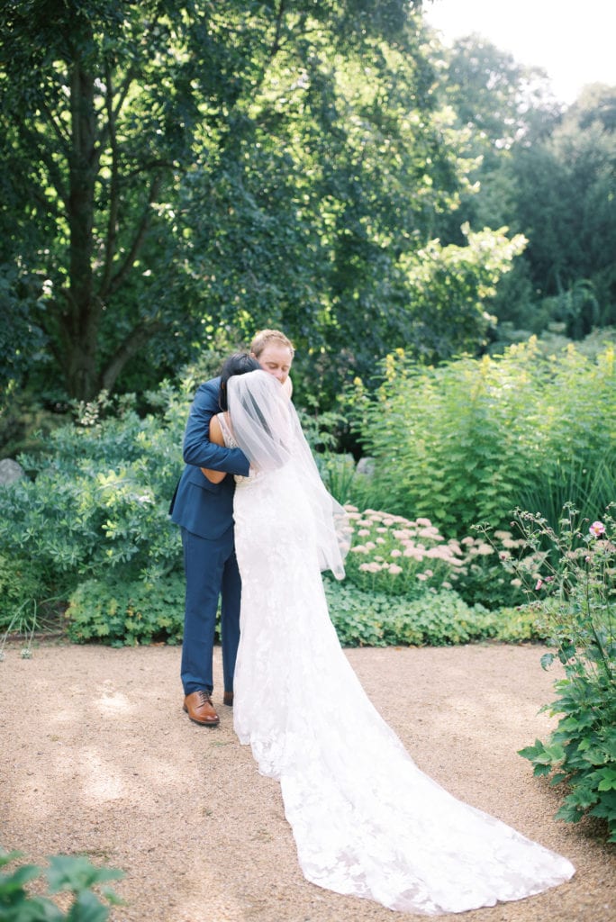 A couple embraces upon seeing each other for the first time during their first look on their wedding day. Must-have wedding photos by Marcela Plosker, a Boston wedding photographer.