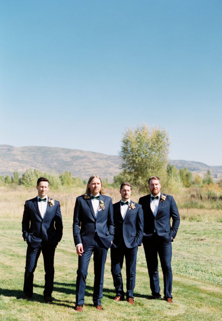 A groom and his groomsmen posing in a green field. Must-have wedding photos by Marcela Plosker, a Boston wedding photographer.