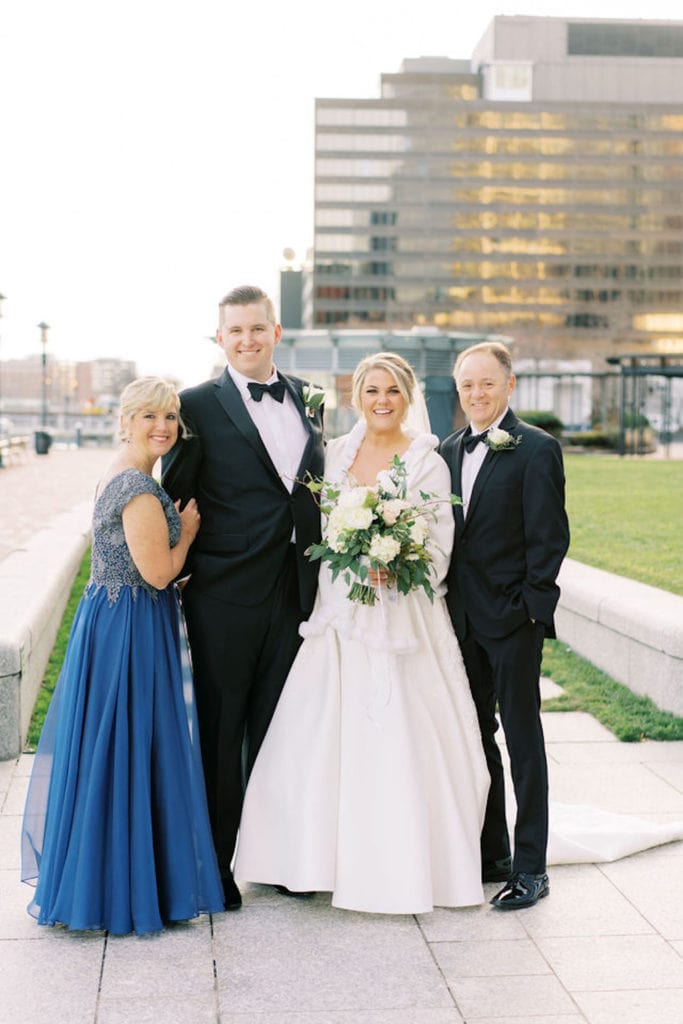 Bride and groom pose in a family photo with the bride's parents as an example of family wedding photos and how to do them right. Photograph by Boston, Massachusetts wedding photographer Marcela Plosker.