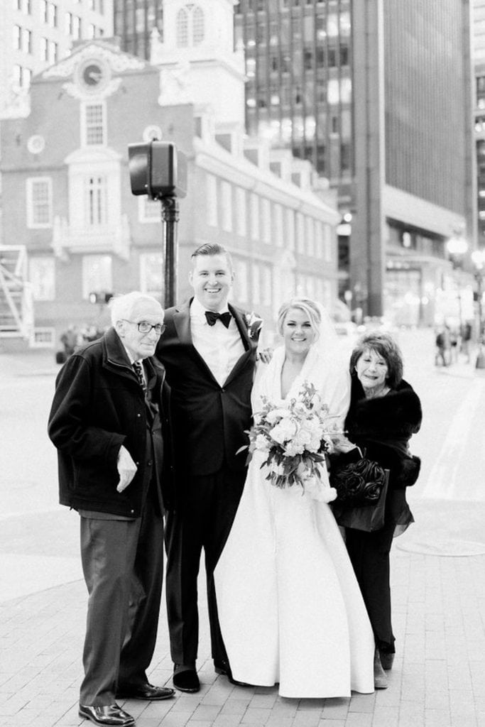 Black and white photo of Bride and Groom posing with their grandparents on the streets of Boston as an example of family wedding photos and how to do them right. Photography by Marcela Plosker, a Boston Massachusetts wedding photographer.