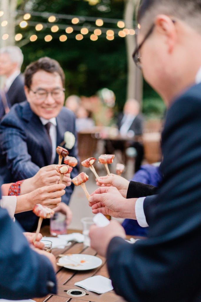 Wedding guests smile while doing a food toast during the wedding reception