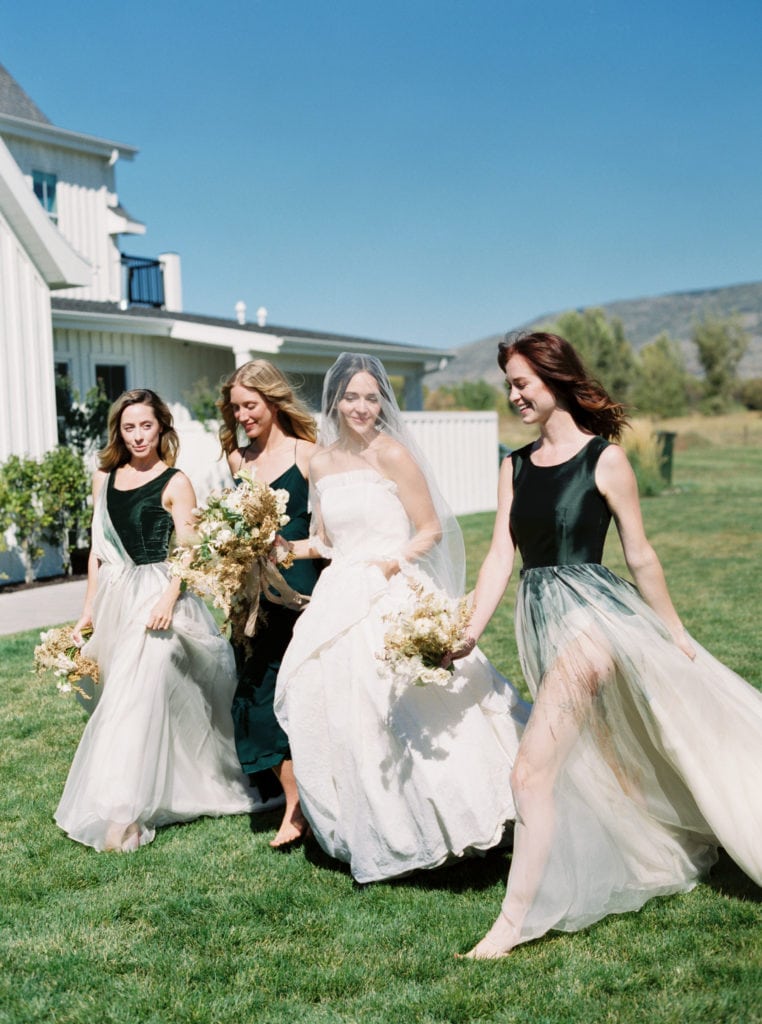 Bride strolling along the wedding venue with her bridesmaids in their flowy dresses and bouquets