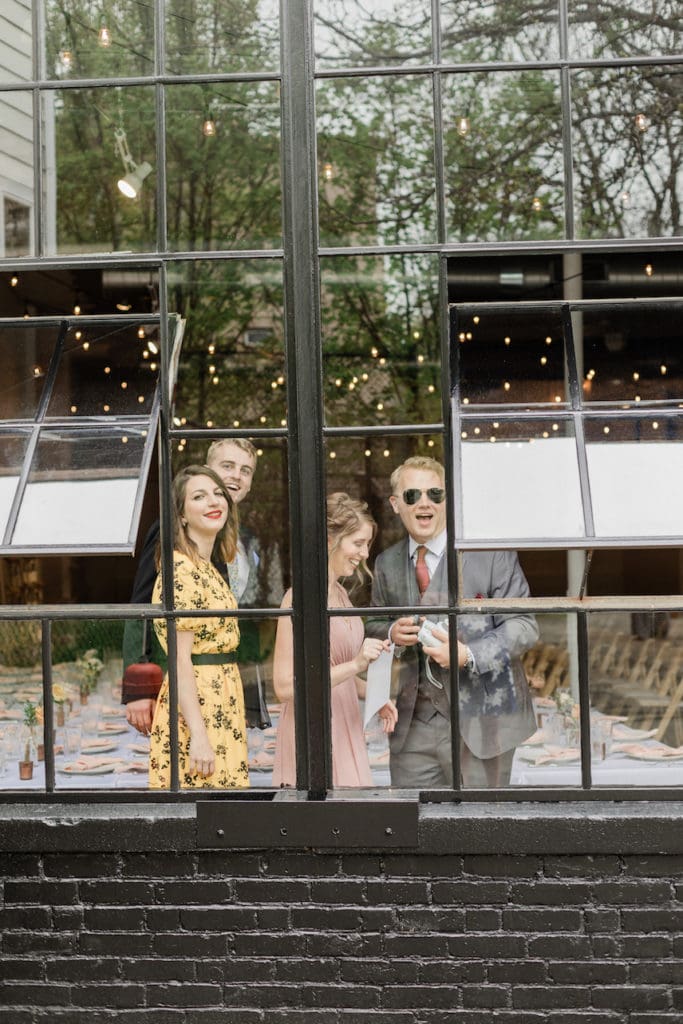 Photo of wedding guests looking out of a window photographed by North Shore, Massachusetts wedding photographer Marcela Plosker