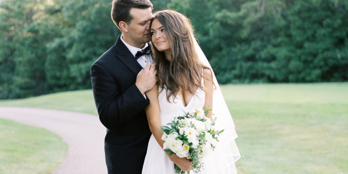 A bride and groom standing in a green field of their magical summer wedding in new england