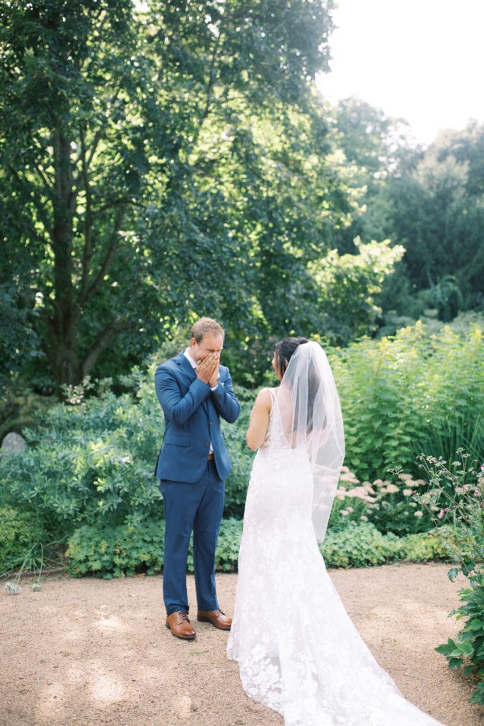 A man covers his face and cries upon seeing his bride for the first time on their wedding day. Must-have wedding photos by Marcela Plosker, a Boston wedding photographer.