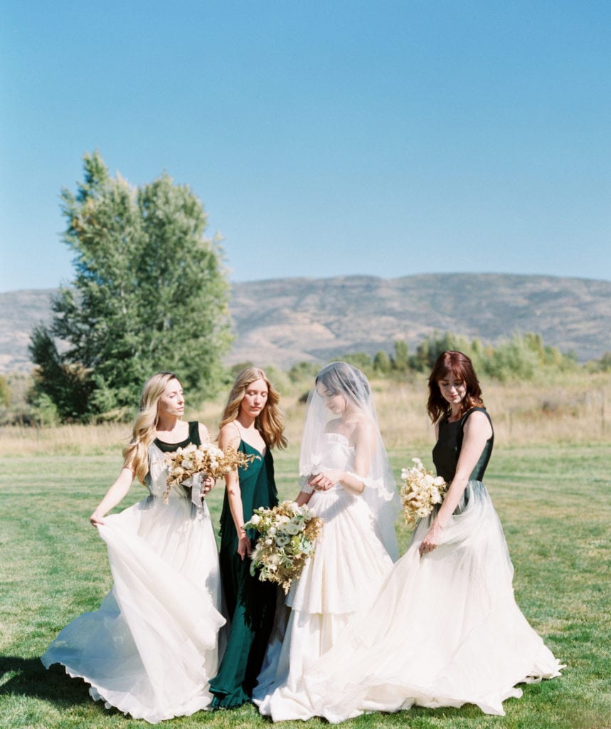 A bride and her bridesmaids posing in a green field. Must-have wedding photos by Marcela Plosker, a Boston wedding photographer.
