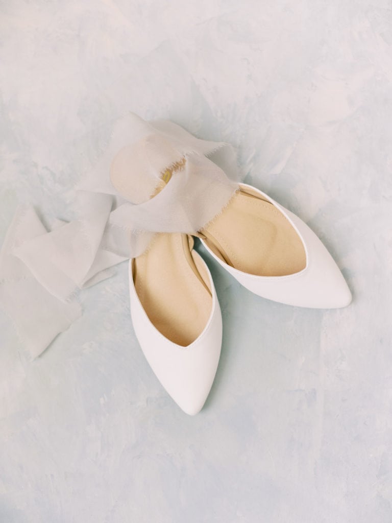 A bride's white wedding shoes with a sheer fabric. Must-have wedding photos by Marcela Plosker, a Boston wedding photographer.