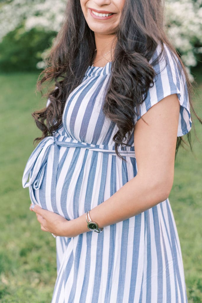 A close up of a pregnant woman embracing her belly as she gets ready to experience The Benefits of Outsourcing as a Mompreneur.