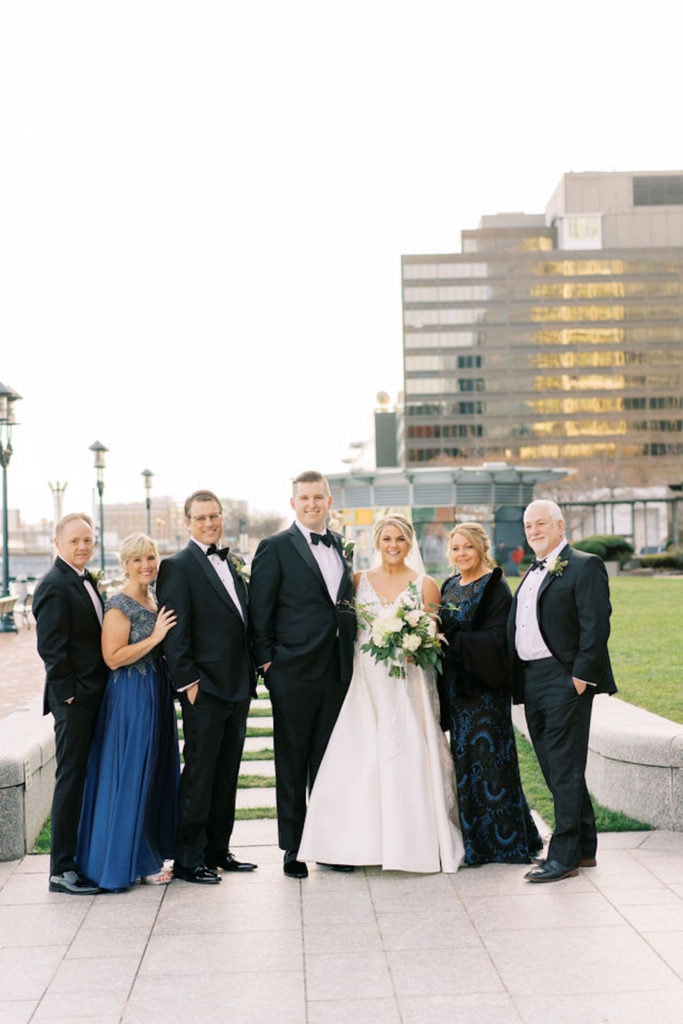 Bride and groom pose in a family photo with the both sets of parents as an example of family wedding photos and how to do them right. Photograph by Boston, Massachusetts wedding photographer Marcela Plosker.