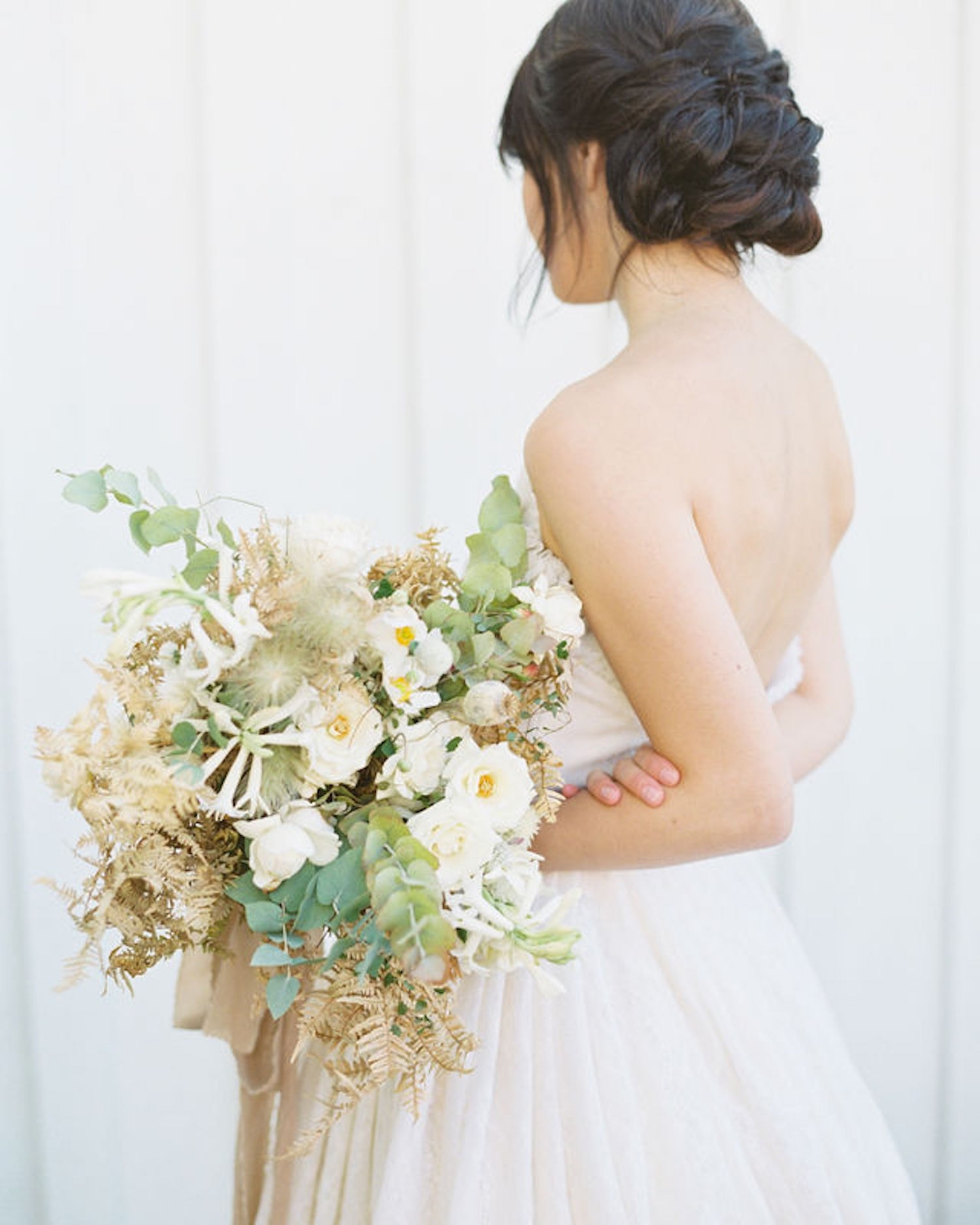 A side shot of a bride holding a lush bouquet of flowers, photo by Marcela Plosker, a Boston wedding photographer who shares 10 questions to ask your wedding photographer before you book.