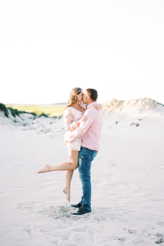 A bride to be and a groom kiss on the beach in North Shore Massachusetts. An example of fine art engagement photo ideas by Boston wedding photographer Marcela Plosker.