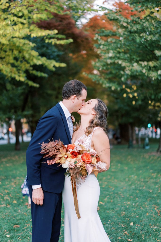A bride and groom kiss in the middle of a garden while getting married in Massachusetts. Image by Boston wedding photographer Marcela Plosker.