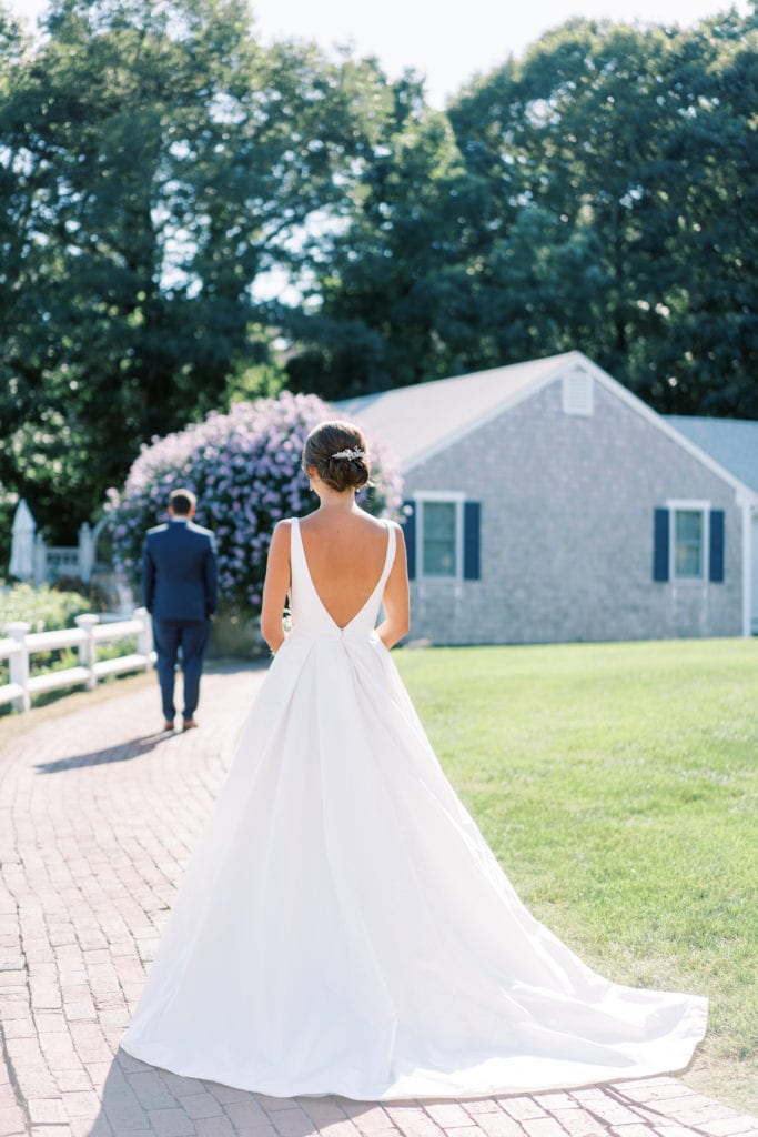 Image of a bride walking up behind the groom during their first look; photograph by Massachusetts wedding photographer Marcela Plosker.