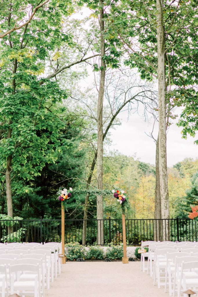 8 Secret Wedding Planning Tips I Wish I Would Have Known. The makeshift wedding arch with flowers on the edges placed in front of the white guest chairs.