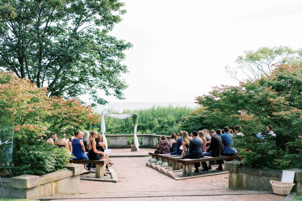 The wedding guests sitting at the wedding venue facing the wedding arch, taken by Marcela Diaz Photography