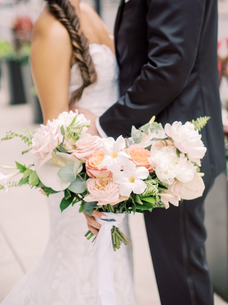 Close-up shot of the vibrant pastel bouquet held by the bride as she and the groom wrap their arms around each other during their Fairmont Copley Plaza wedding