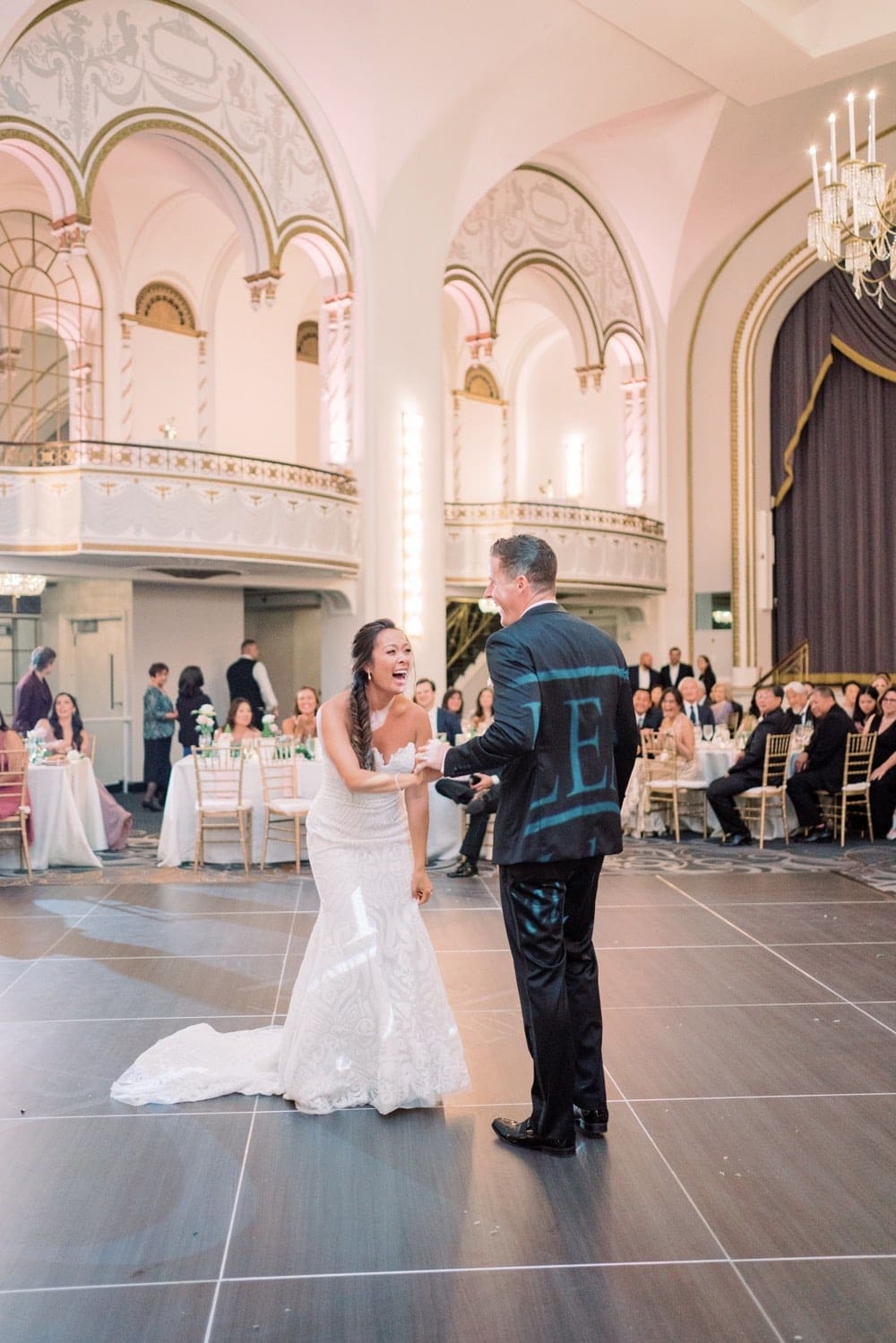 Bride and groom playfully sharing laughs on the dance floor as they prepare to dance, taken by Marcela Diaz Photography