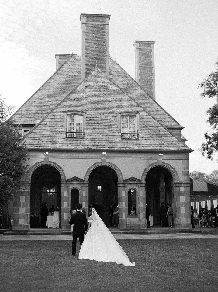 Bride in a cathedral veil walking with her groom toward the reception at Glen Manor House